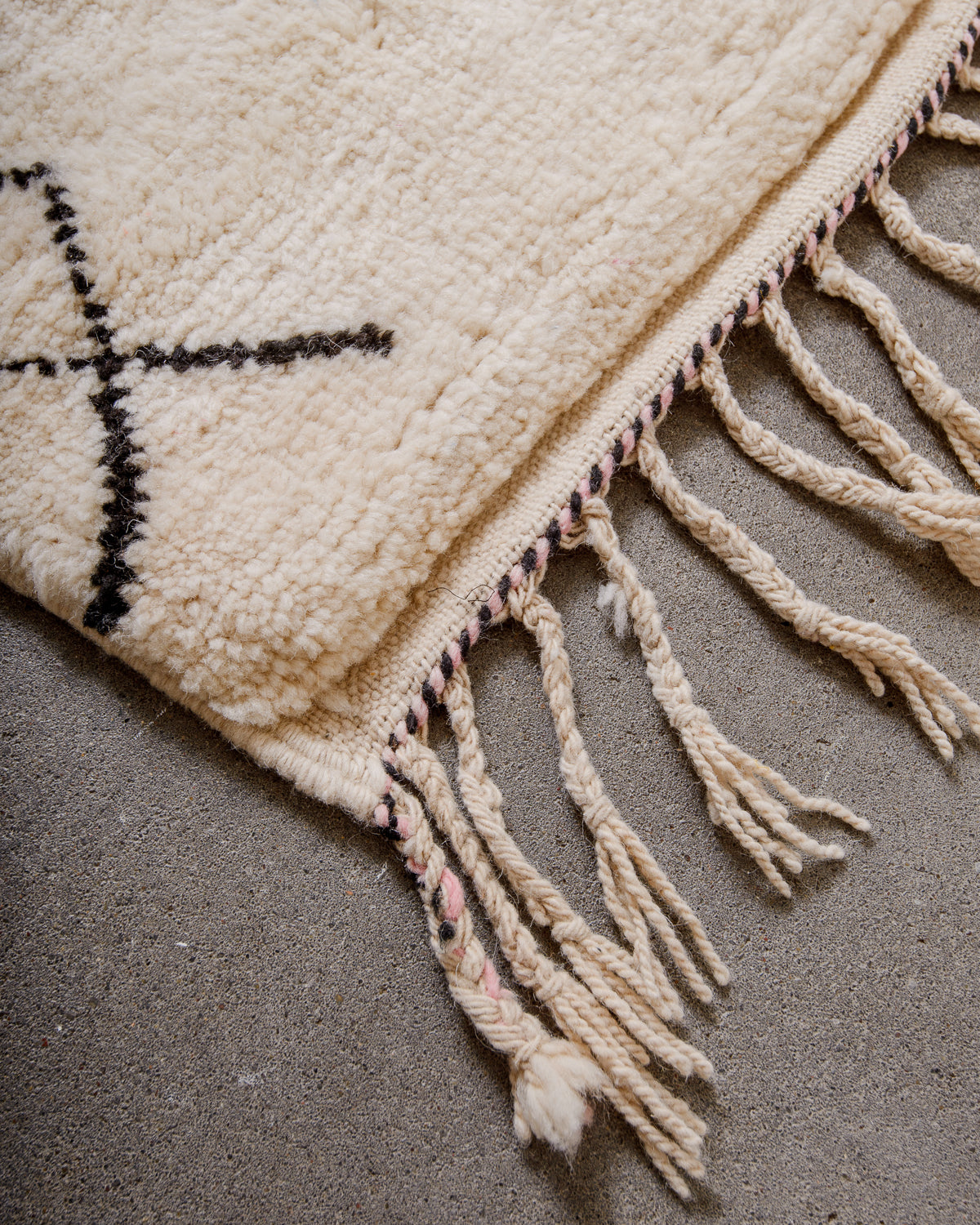 Corner of rug made of thick wool pile and natural wool tassels.